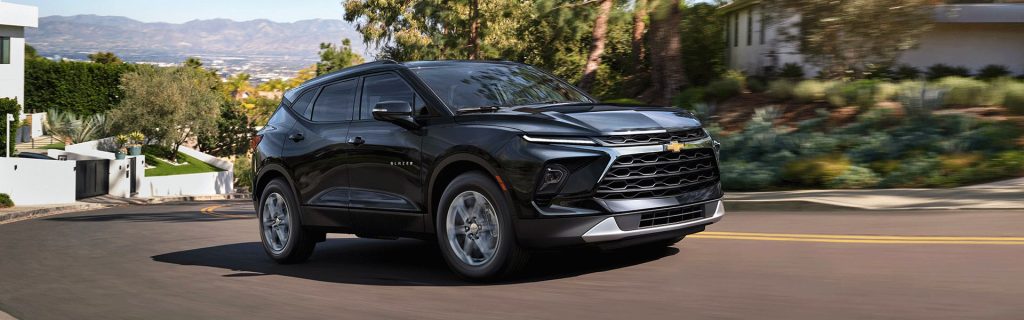 Black Chevrolet Blazer driving on a winding road through a hillside neighborhood.